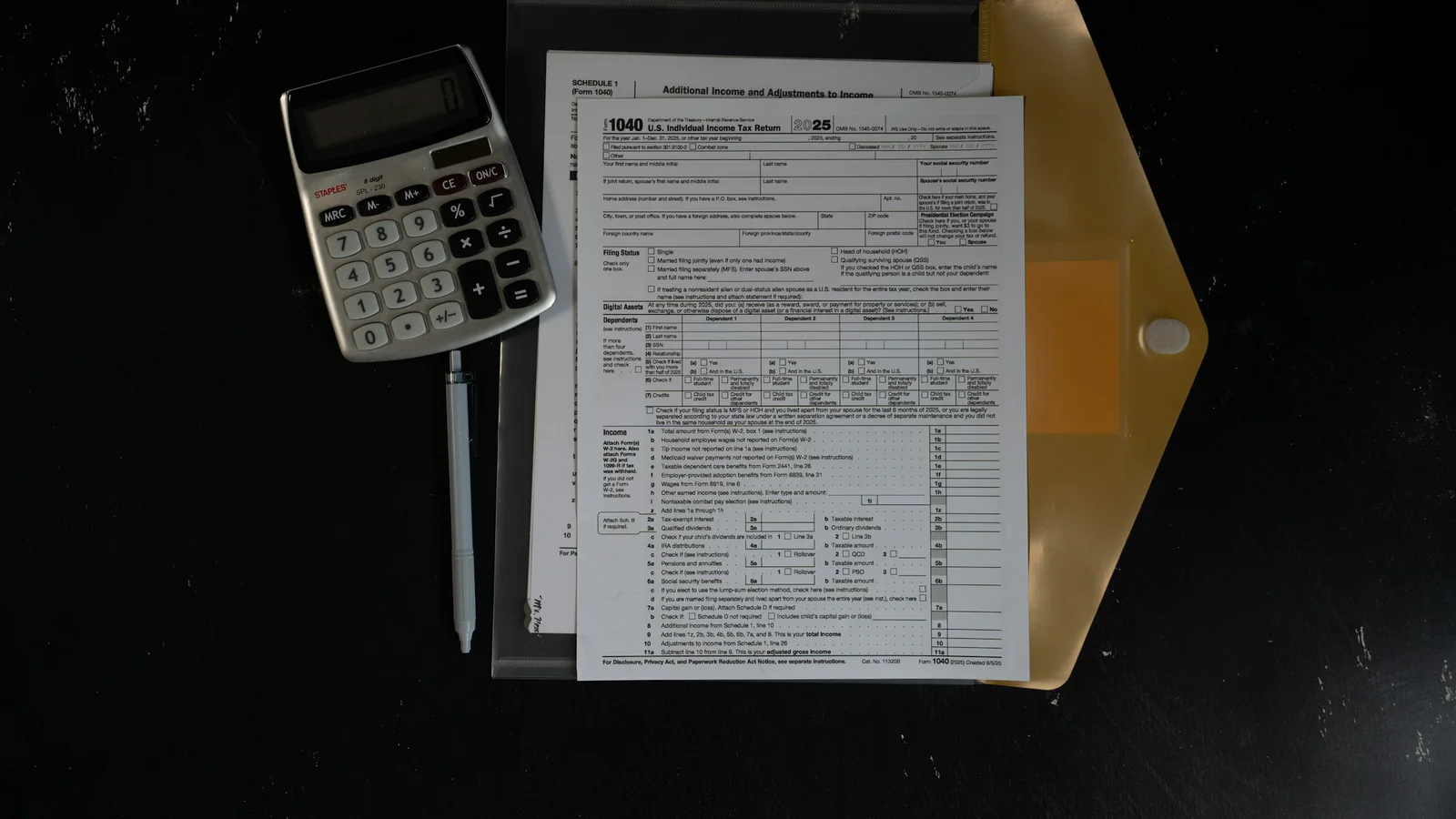 Calculator and blank 2025 United States tax forms on a dark work surface